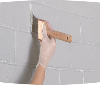 A person painting a brick wall with a paint brush
