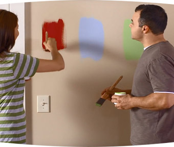 A man and a woman testing out different paint colors on the wall