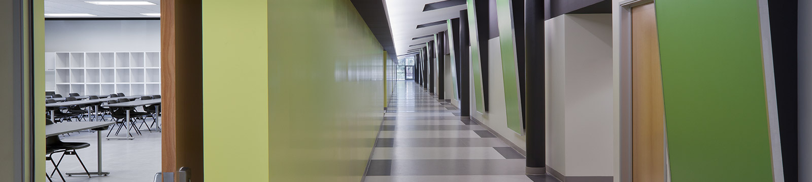 An image of a large empty classroom hallway with a green, gray and white color combination.
