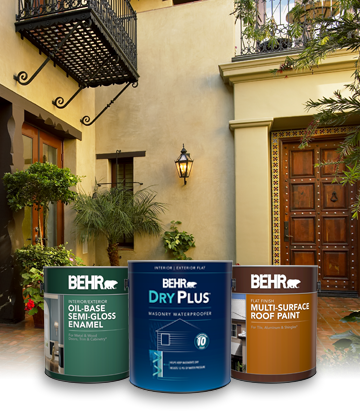 Three cans of Behr Paint with tan house in the background