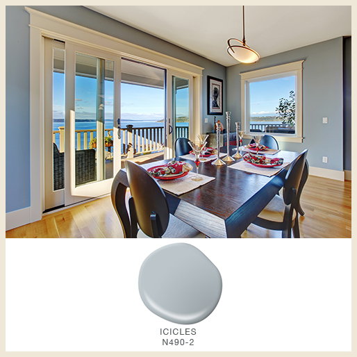 A dining room with a lake view and walls painted in light blue-toned gray color called Icicles.