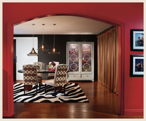 An elegant dining room featuring black and red walls.  Dining hardwood flooring is a dark brown with zebra rug. 