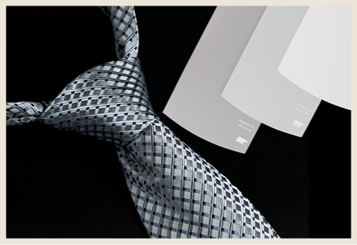 A close up detail of a silk tie and multiple gray-toned paint swatches.