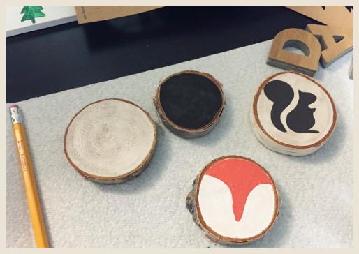 Birch rings being painted with woodland creature stencils and freehand designs..