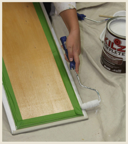 A woman's hand applying primer to metal cabinet edges.