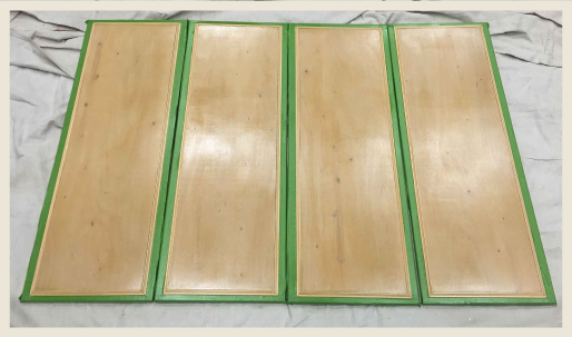 Four wood panels after being sprayed with shellac.