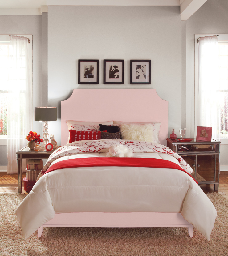 A bedroom with the headboard and footboard painted in Cupcake Pink. Walls of room are painted in white. The Bedding is cream and red hues.