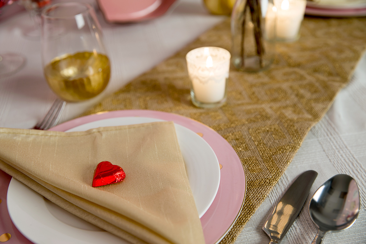 This is a close up of the table setting with the plates, silverware, candle and cup. 