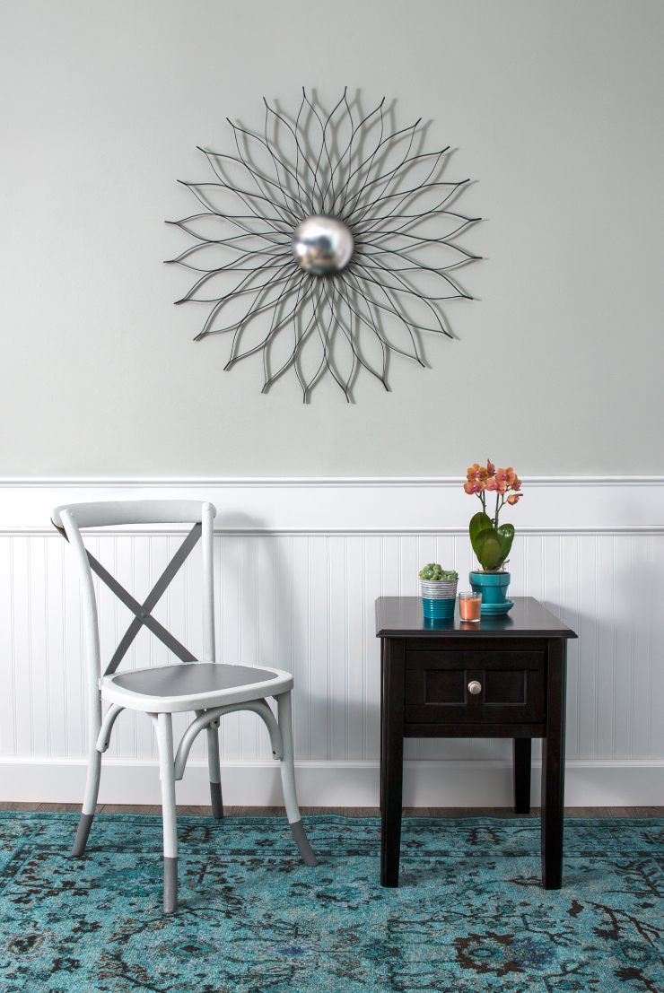 Sitting area with a white and gray chair, side table. Wall behind is painted, top half in gray, bottom half is white.