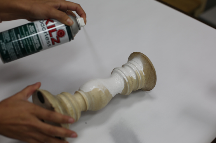 Spraying primer onto a wood candle-holder.
