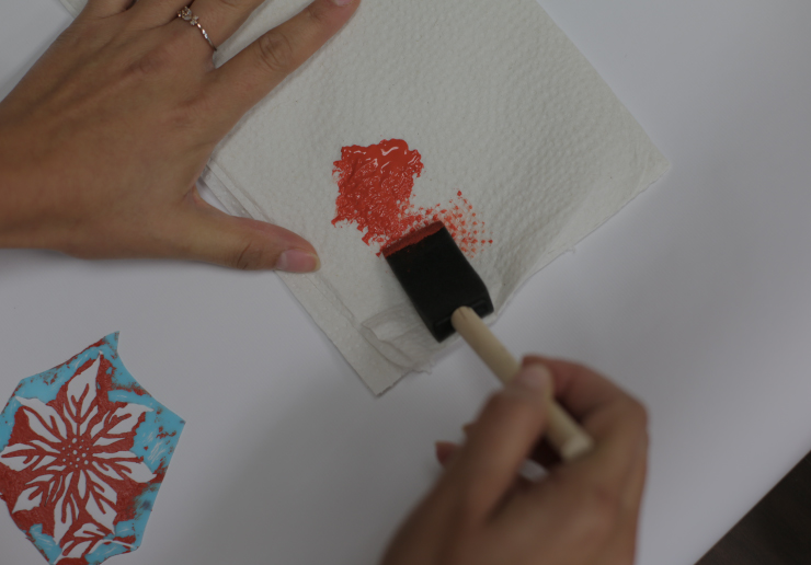 Dabbing excess paint onto a napkin.
