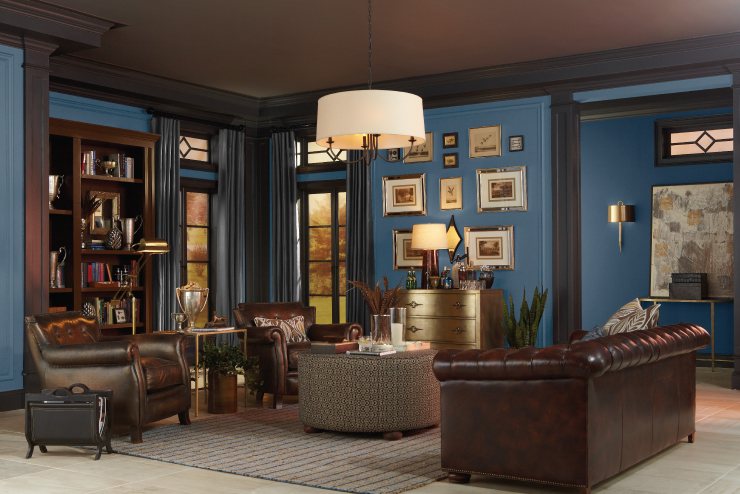 A classic masculine living room featuring blue painted walls, dark woodwork and dark brown leather furniture.