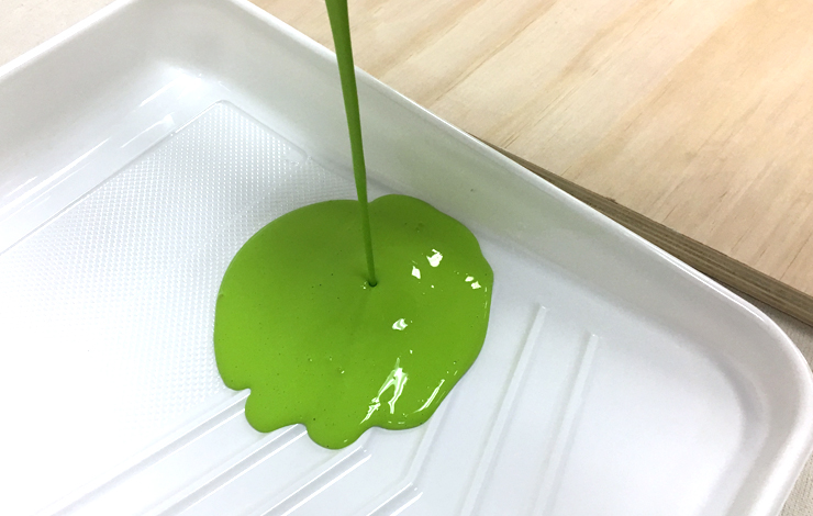 Paint tray with bright green paint pouring into it.