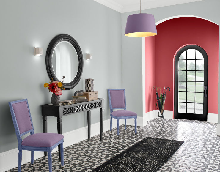 An interior entryway painted in a bright red color with white trim. As you walk into the home the walls are painted gray and the rooms décor is colored in blue and purple.