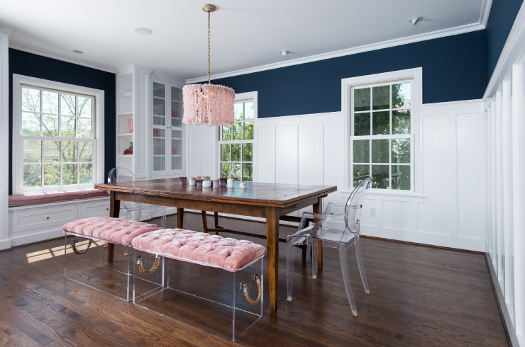 A dining area with pink colored bench style chairs and a pink chandelier
