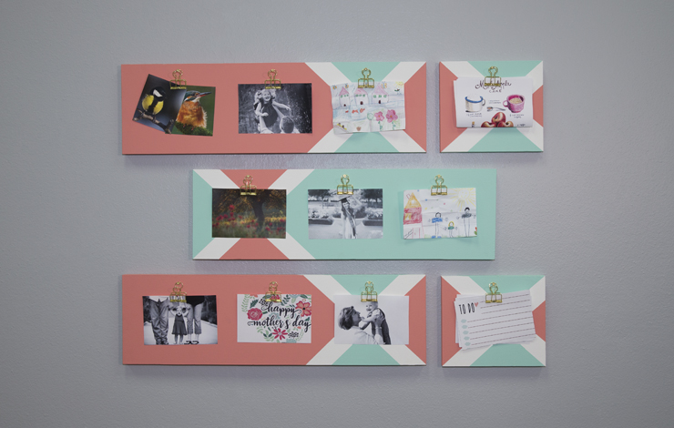 A decorative clipboard with images hanging from it. The clipboard is painted in peach, mint and white colors.