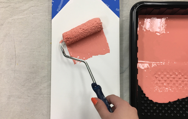 Person painting the peach color on the board.