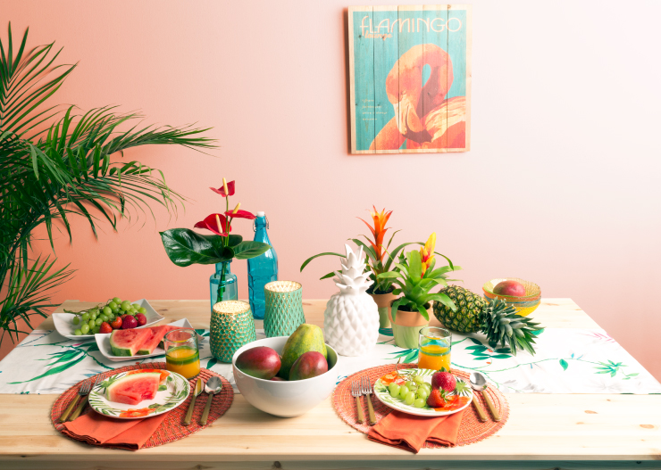 An exterior table setting decorated with stylish, fun plates and decorative elements. A wall painted in a light color called Flamingo Feather.