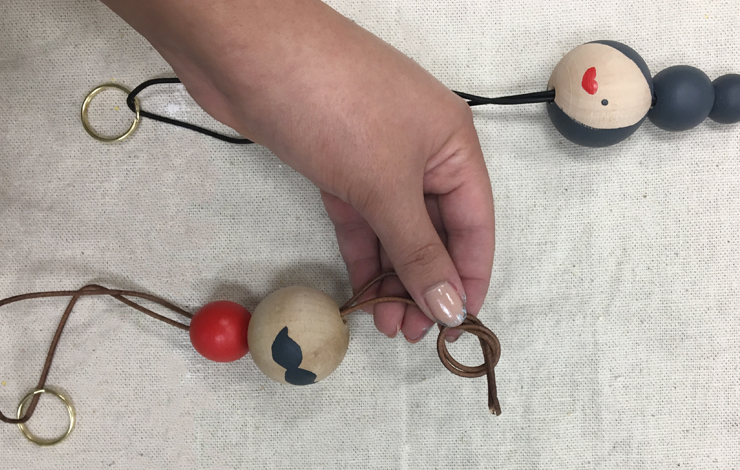 Adding leather rope through the holes in the painted wood balls