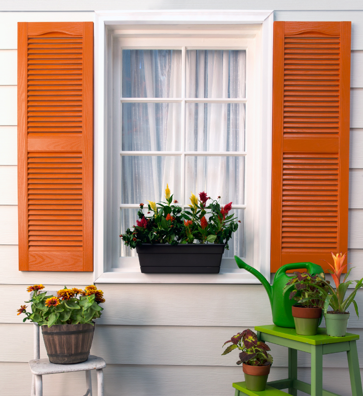 Exterior home showing a closeup of a window with shutters painted in an orange paint color; Civara