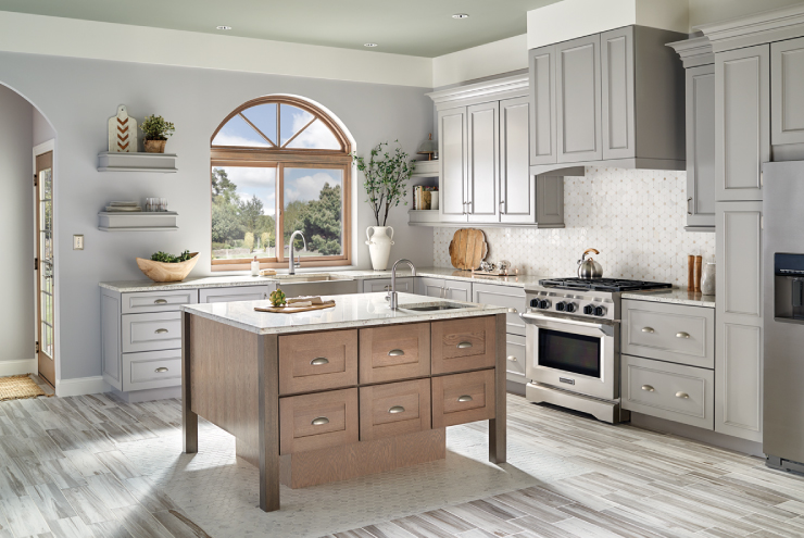 A kitchen painted in a gray color, cabinets are the same color. Trim is white.