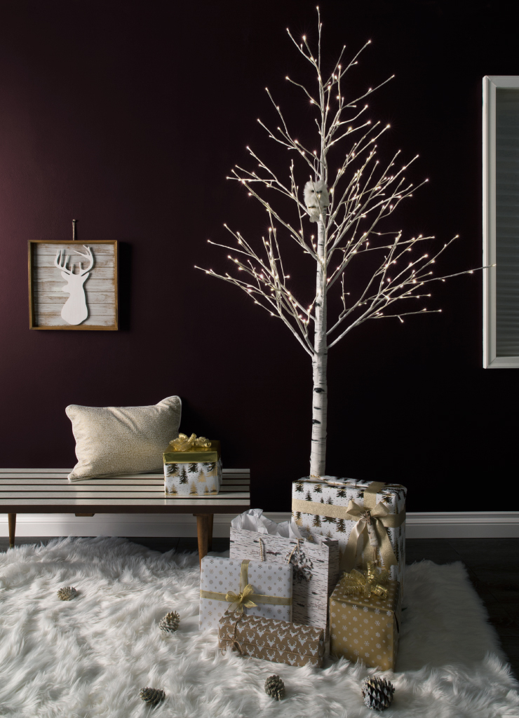A sitting area painted in Nocturne Shade. There is a wood bench against the wall. A branch style tree with lights standing next to the bench. Under the tree are gifts wrapped in white and gold holiday paper.