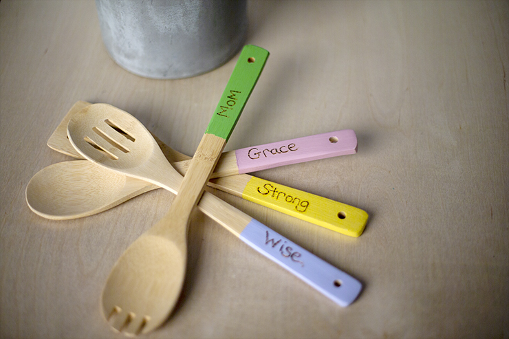 The finished project: Wood utensils handles painted in green, pink, yellow and purple with inspirational words written on them.