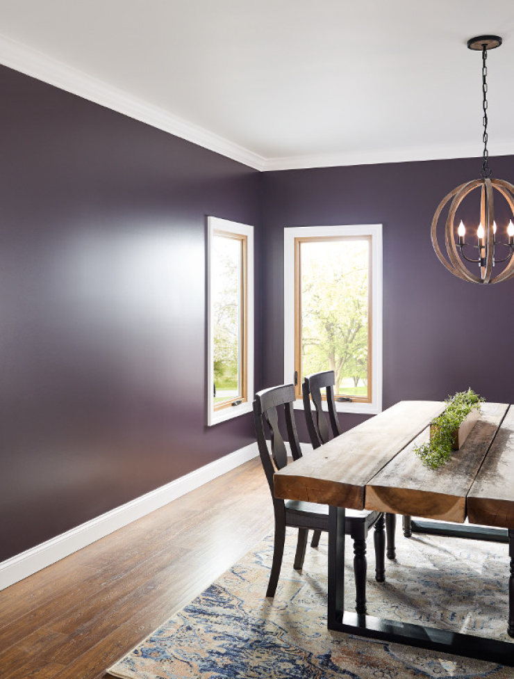 A simple dining room areas featuring glossy painted walls in a plum purple color. 