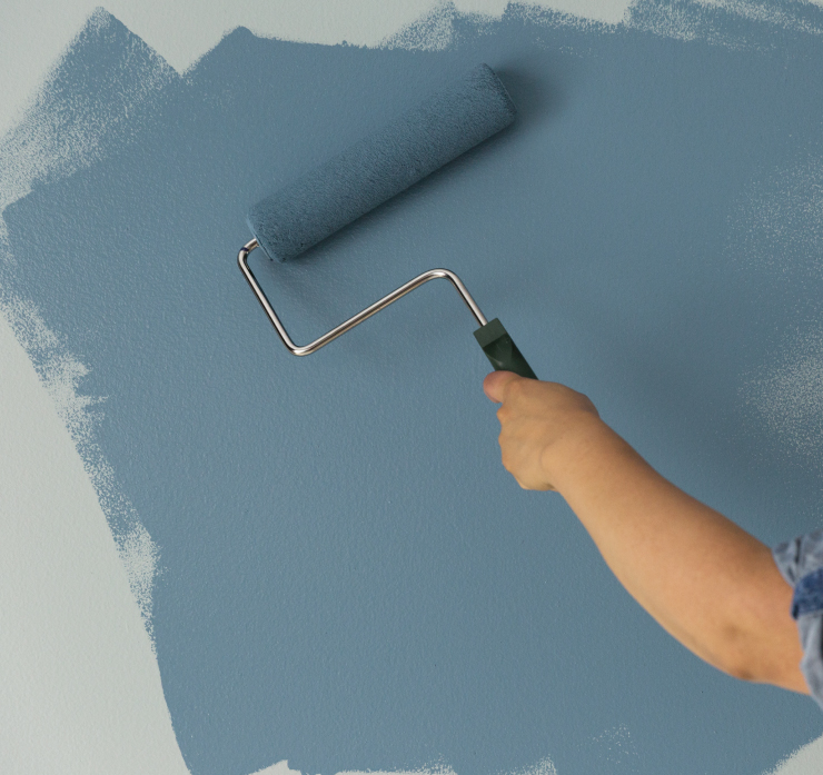A person painting over light blue color with second coat of paint in a blue color called Blueprint. 