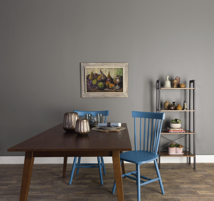 A simple dining area featuring a dark wood table and two blue chairs. 
