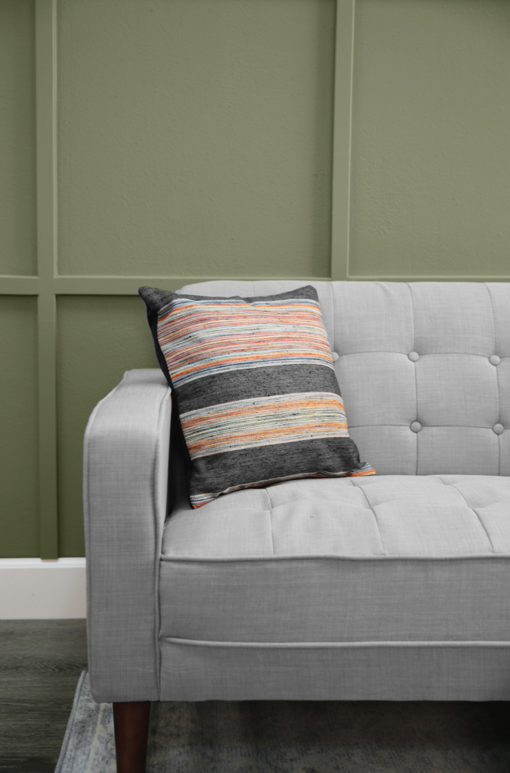 A grey couch against a paneled wall painted in Ecological. 
