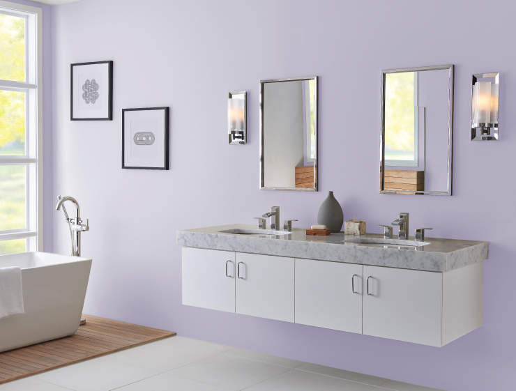 A large spa-like bathroom with wall mount sink furniture and a modern white ceramic tub. A wall size window allowing ample natural light into the room.  Walls painted in light purple color called Fanciful. 