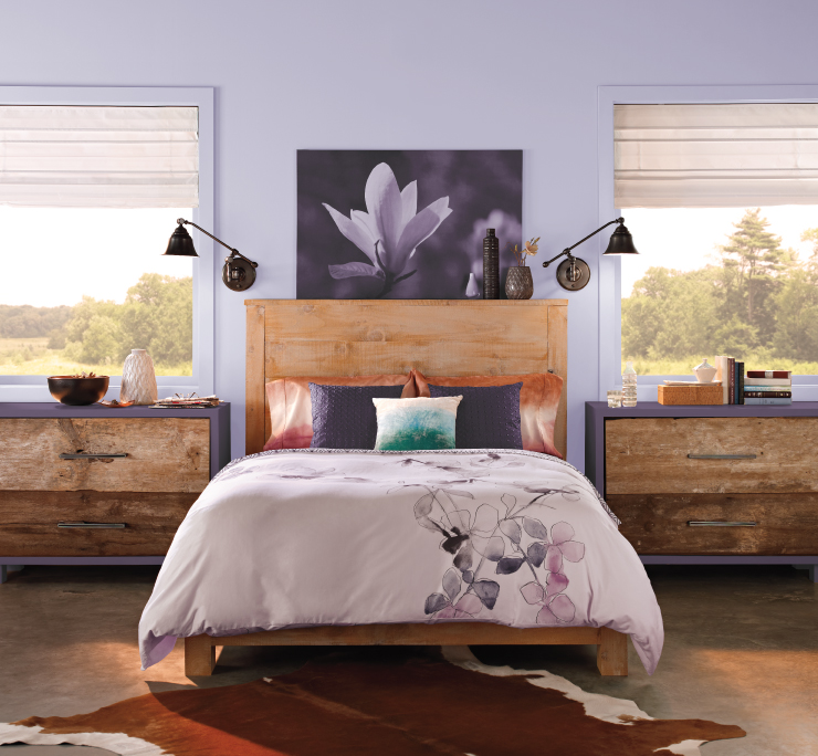 A modern rustic bedroom featuring cleaned lined and rough wood furniture.  Wall with two large windows, painted in a light purple color.  