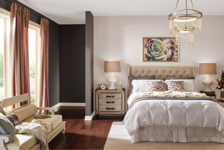 A classic pink and dark gray bedroom with a brick wall, two big windows and comfy furniture. 