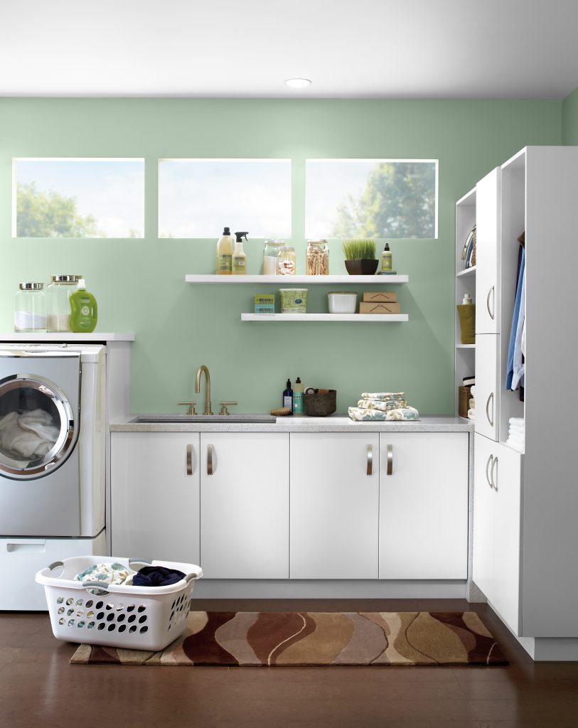 A contemporary light green laundry room with abundant natural light,  white cabinetry and washing machine. 