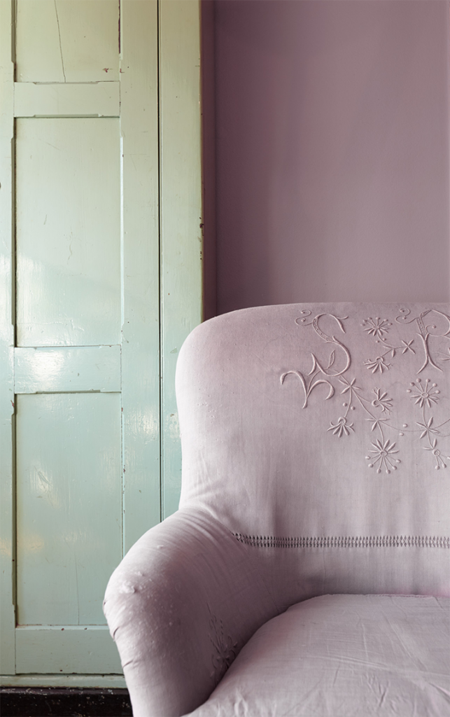 A  wall painted in Standing Ovation to compliment a green door and match the purple chair that is sitting in front of the wall.
