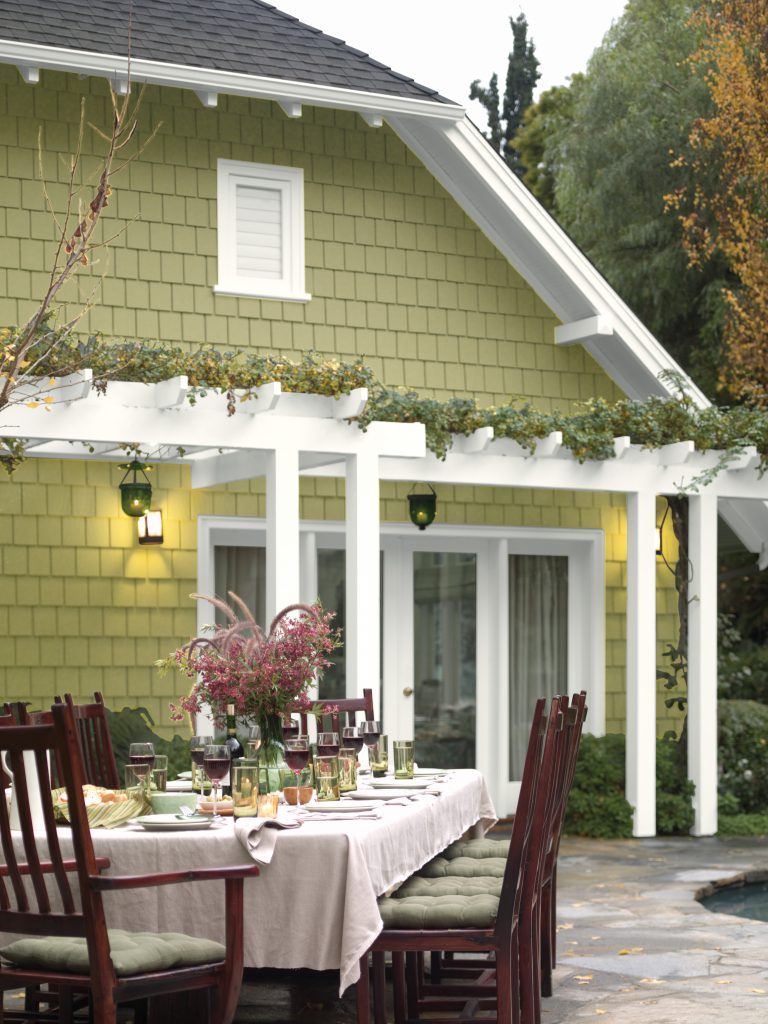 An exterior home painted in Back to Nature. The patio is set up with a long table for a large dinner party.
