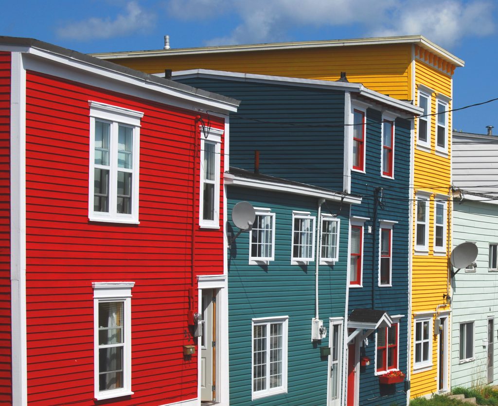 A view of a few different colorful homes taken from the side of the road.
