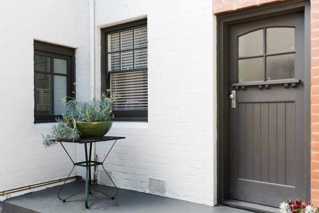 Entry porch and dark gray front door of an art deco style apartment. 