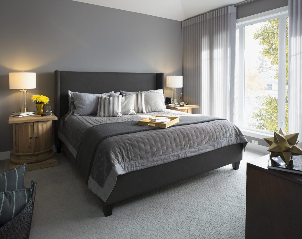 Elegant, modern bedroom showcase various gray tones.   An upholstered gray bed dressed with simple yet  elegant bedding.