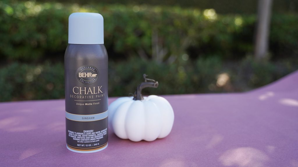 Product shot of Behr Chalk Decorative paint spray paint with a white pumpkin. 