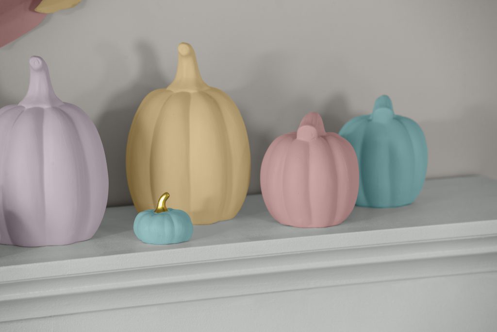 A close up detail image of ceramic pumpkins painted in multi-pastel tones. 