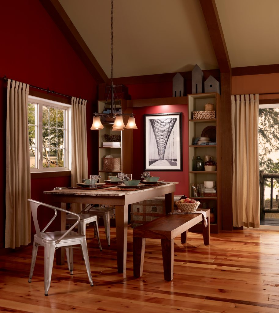 A Craftsman style home interior featuring a dining area with eclectic furniture.  Ceiling with wooden beams. Walls are painted in red color called Red Pepper. 