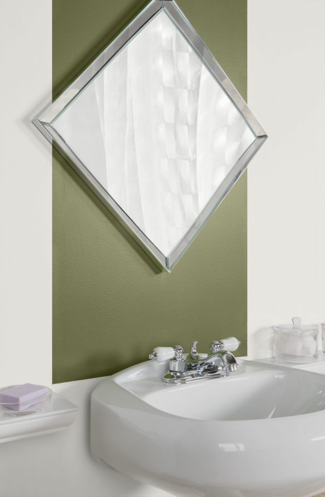 Close-up view of bathroom showing the green stripe above the pedestal sink painted in Secret Meadow. Mirror is placed in front of stripe above sink.