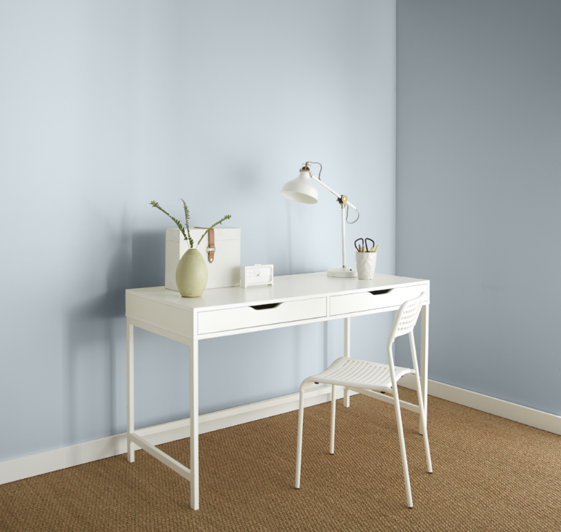 A casual home office area with all white desk and chair. The decor is very clean and minimal looking.  The walls are painted in a light blue color called Light Drizzle. 