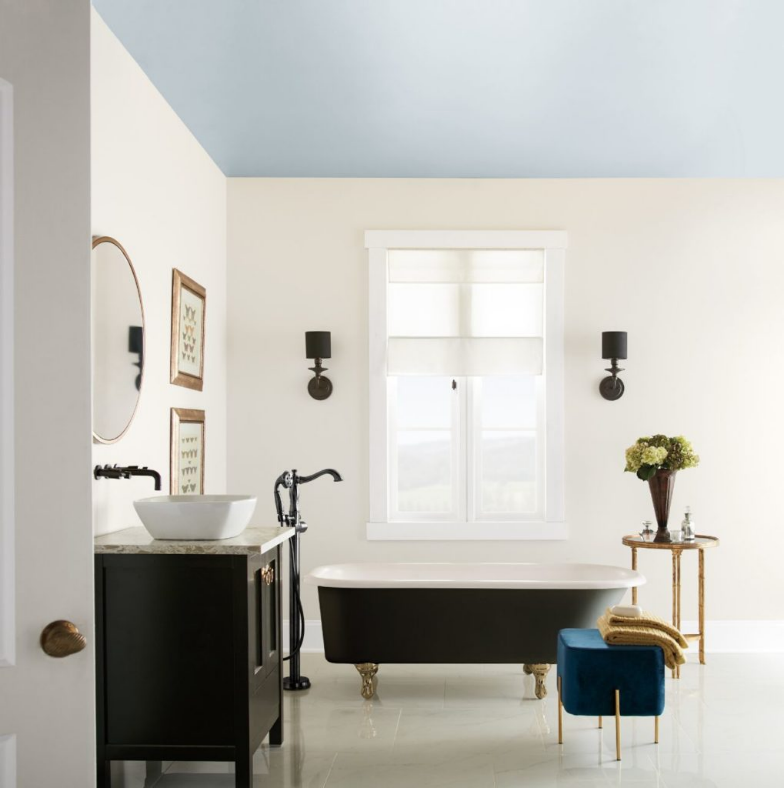 A classic-modern bathroom, featuring a black clawfoot tub, sconces and sink cabinet.  The room is paint in white color called Painter's White and the ceiling is painted in light blue color called Light Drizzle. 