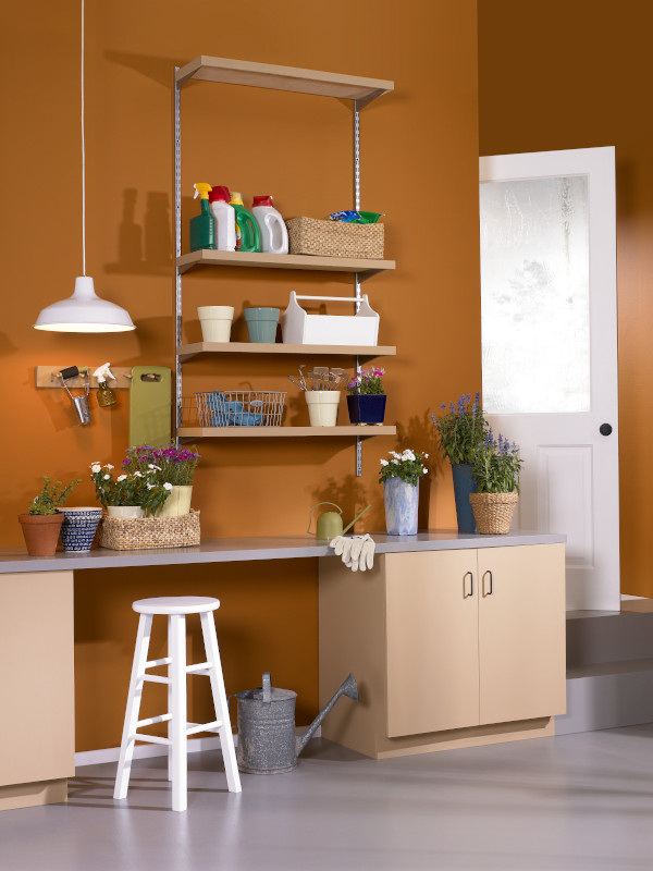 The interior of a garage with organization shelves and potting bench. Wall are painted in orange color called Rumba Orange. 