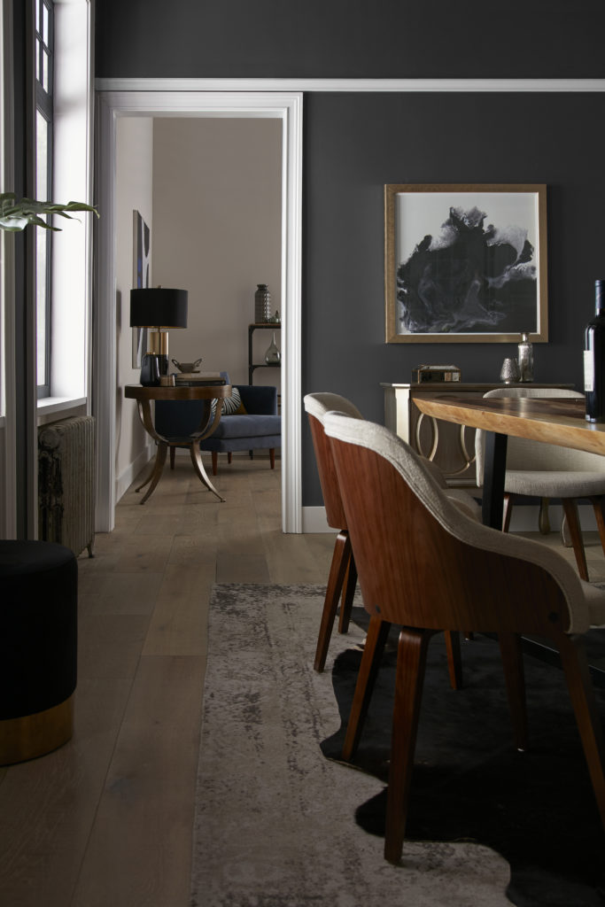 A vertical image of an elegant black dining room painted in paint color called Broadway.   