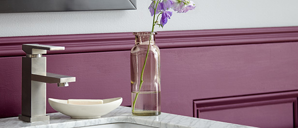 A close-up detail of a half bath wall and sink, the small space features a statement magenta lower wall. 