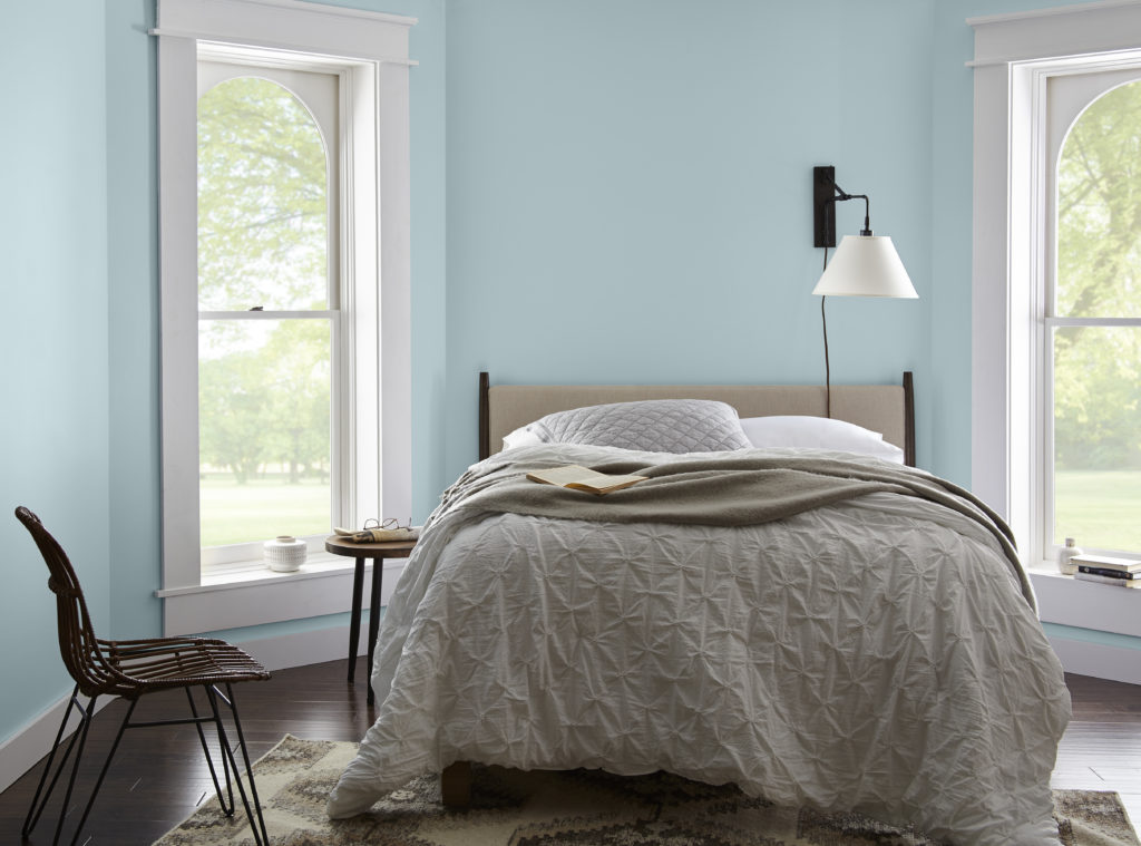 A casual bedroom, there is a window on both side of the bed which lit up the room and create an open and airy feel. The walls are painted in a light blue color called Dayflower. 